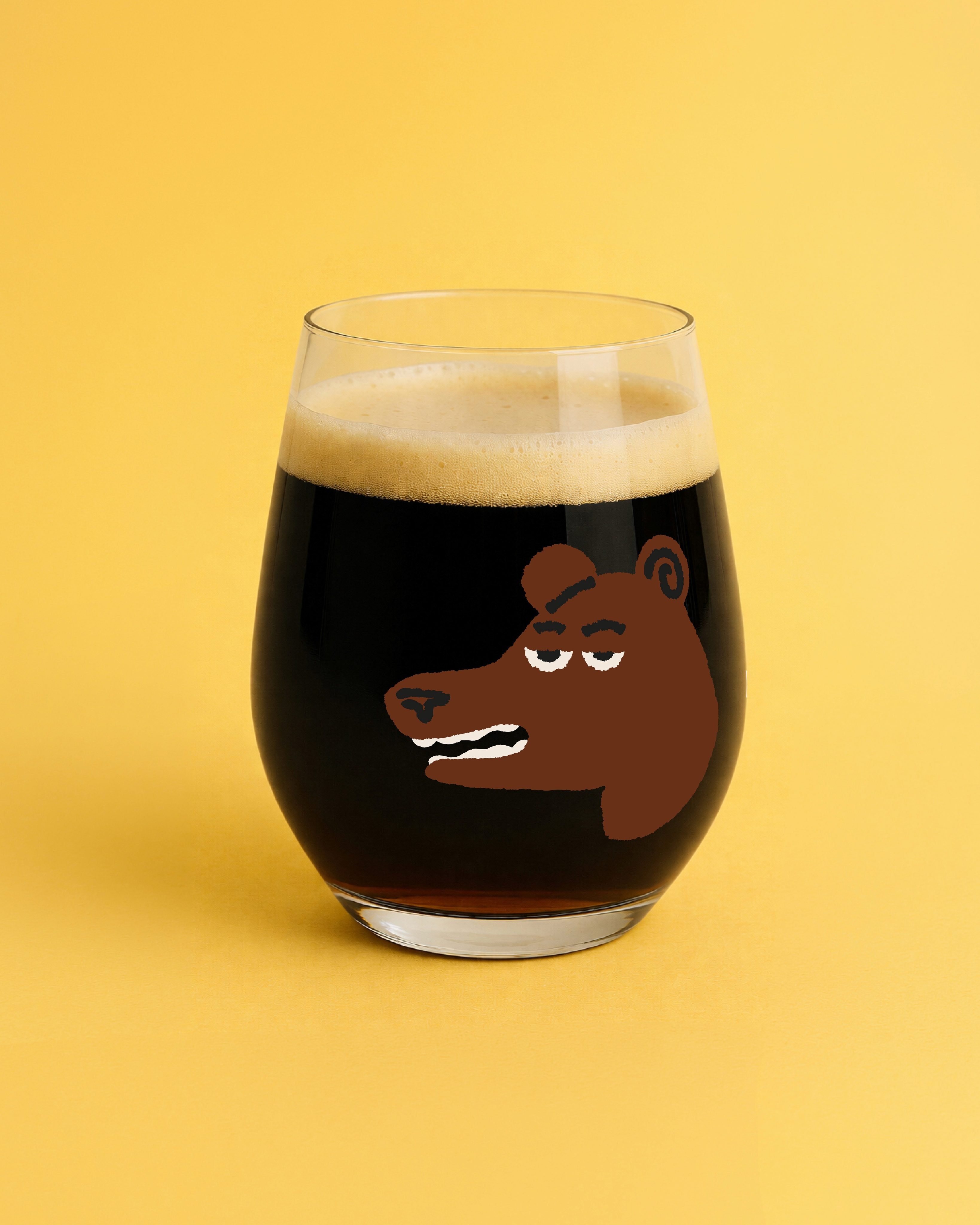 Glass of dark beer printed with the festival's grinning brown bear character on a yellow background