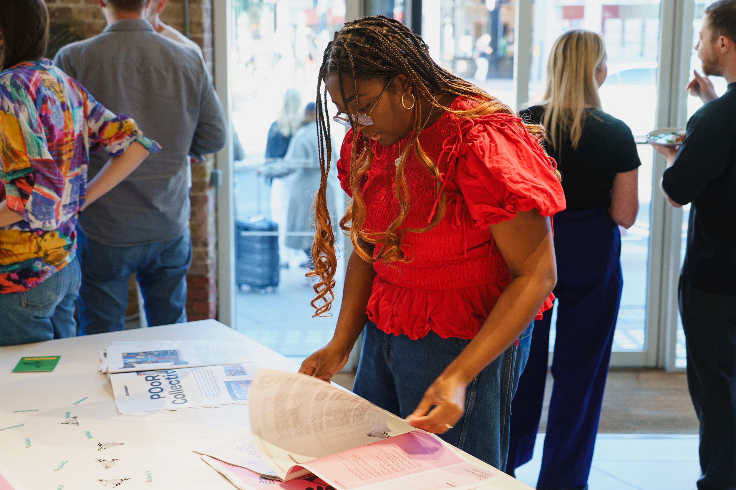 A guest in a red top leafs through printed pieces laid out on a table